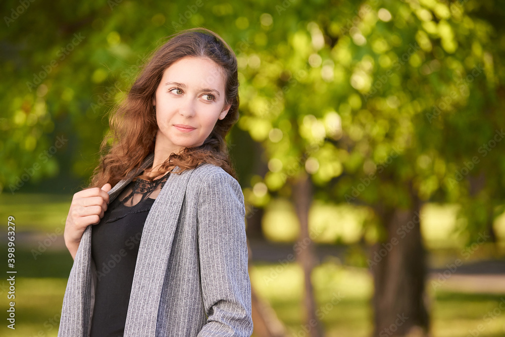Pretty young woman. Outdoor portrait. Curly long hair. Casual clothes. Female businessperson. Student portrait. Professional manager. Confident person. Public park. Success people face. Look side Pretty young woman. Outdoor portrait. Curly long hair. Casual clothes. Female businessperson. Student portrait. Professional manager. Confident person. Public park. Success people face. Look side