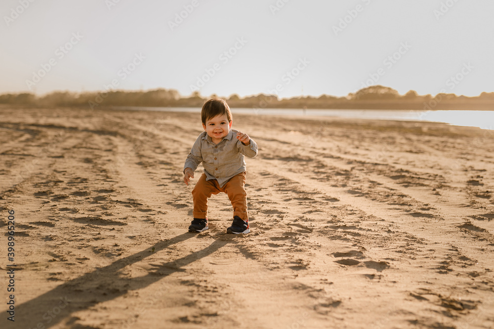 cute toddler baby boy walking on the sandy beach