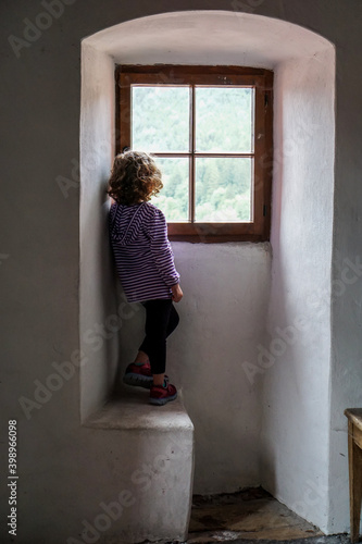 Slika na platnu Young girl standing in an alcove gazing out a castle window