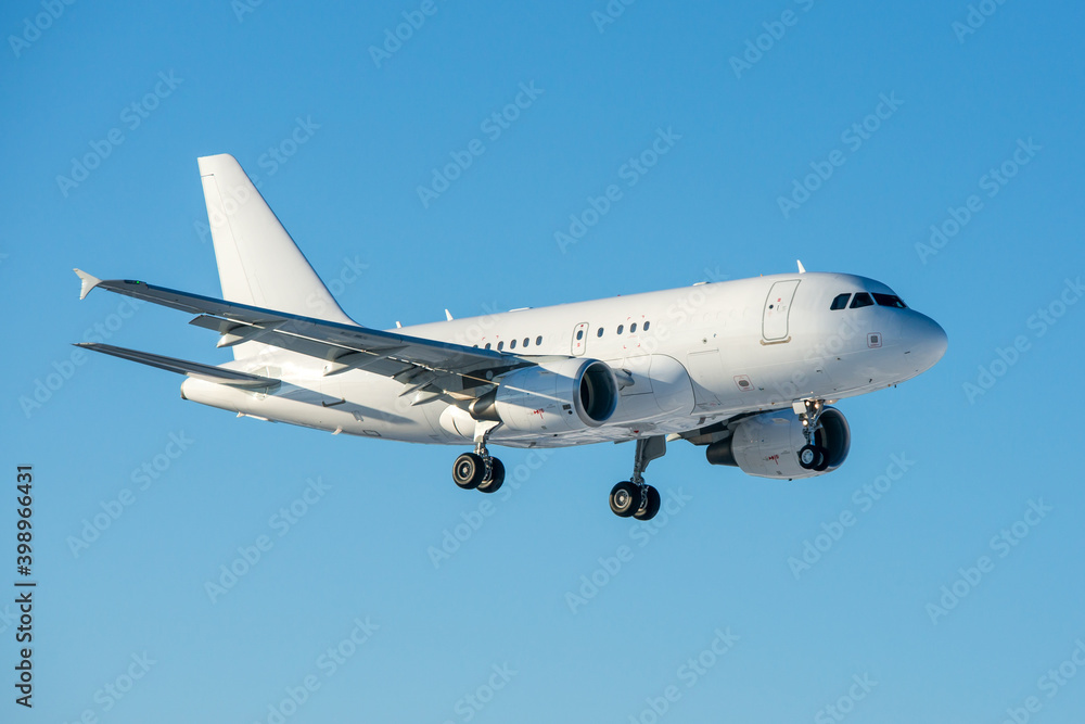 White modern business jet landing at the airport at clear sunny cold winter day.