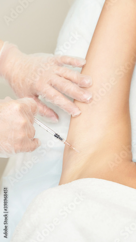Armpit injection at spa salon. Doctor hands. Closeup view. High quality. Pretty female patient. Beauty treatment. Healthy skin procedure. Young woman head. Light background. Hyperhidrosis rejuvenation