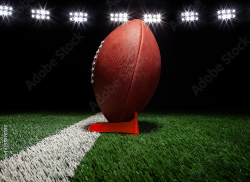 Foto Low angle view of a football on a tee on black background under lights