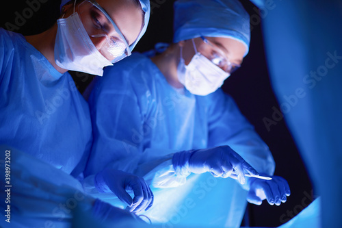 Doctors team in surgery in a dark background.