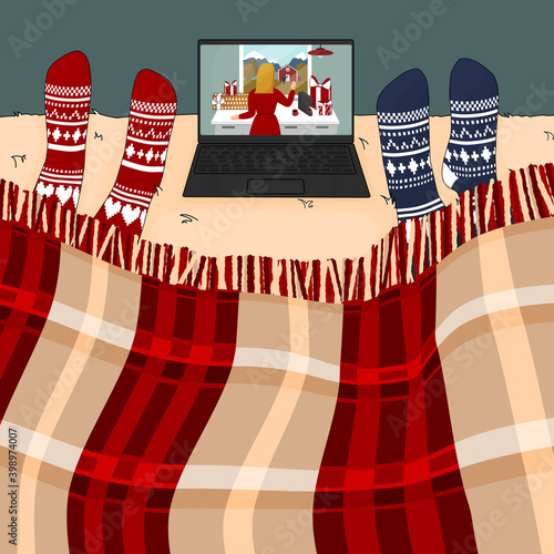 People in knitted socks are watching film on the laptop in the Christmas time