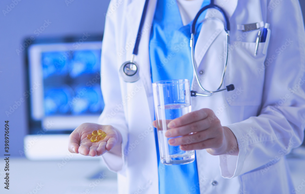shot of doctor's hands holding pills and glass of water at clinic. shot of doctor's hands holding pills and glass of water at clinic.