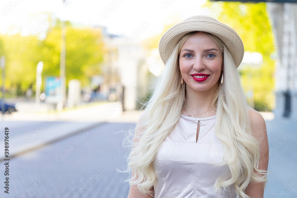 beautiful blonde dressed in dress and hat posing on the city streets
