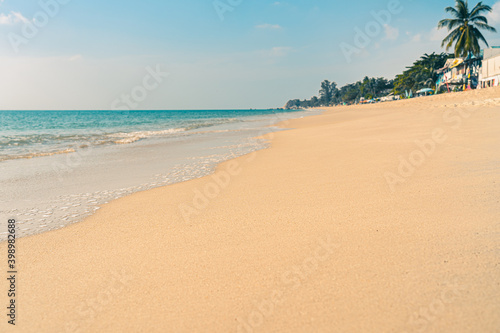 Tropical deserted sandy beach with clear water on a sunny summer day. Surf on the seashore  in the background blue sky  palms and mountains 