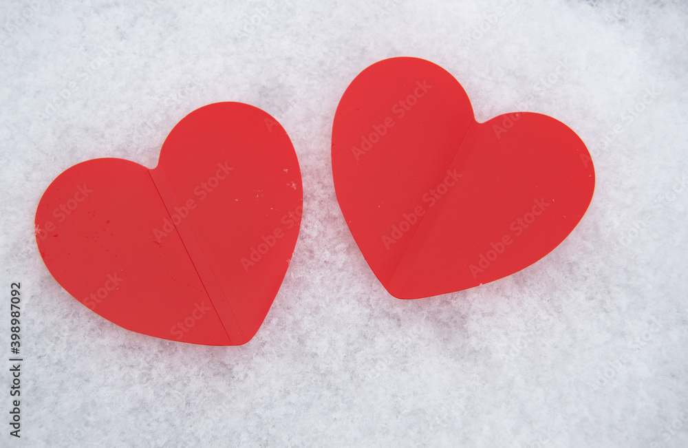Two beautiful romantic red hearts together on a white snowy background. The concept of love and Valentine's Day Two beautiful romantic red hearts together on a white snowy background. The concept of love and Valentine's Day