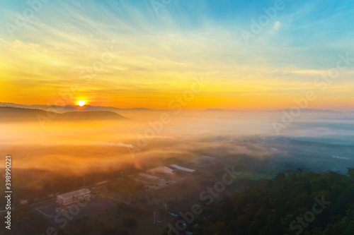 Aerial view of fantastic foggy landscape glowing while sunrise in the morning. Colorful landscape with high mountains foggy cover in sunset or sunrise .Top view. Nature