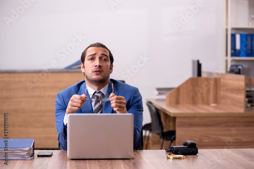 Young male employee sitting at workplace