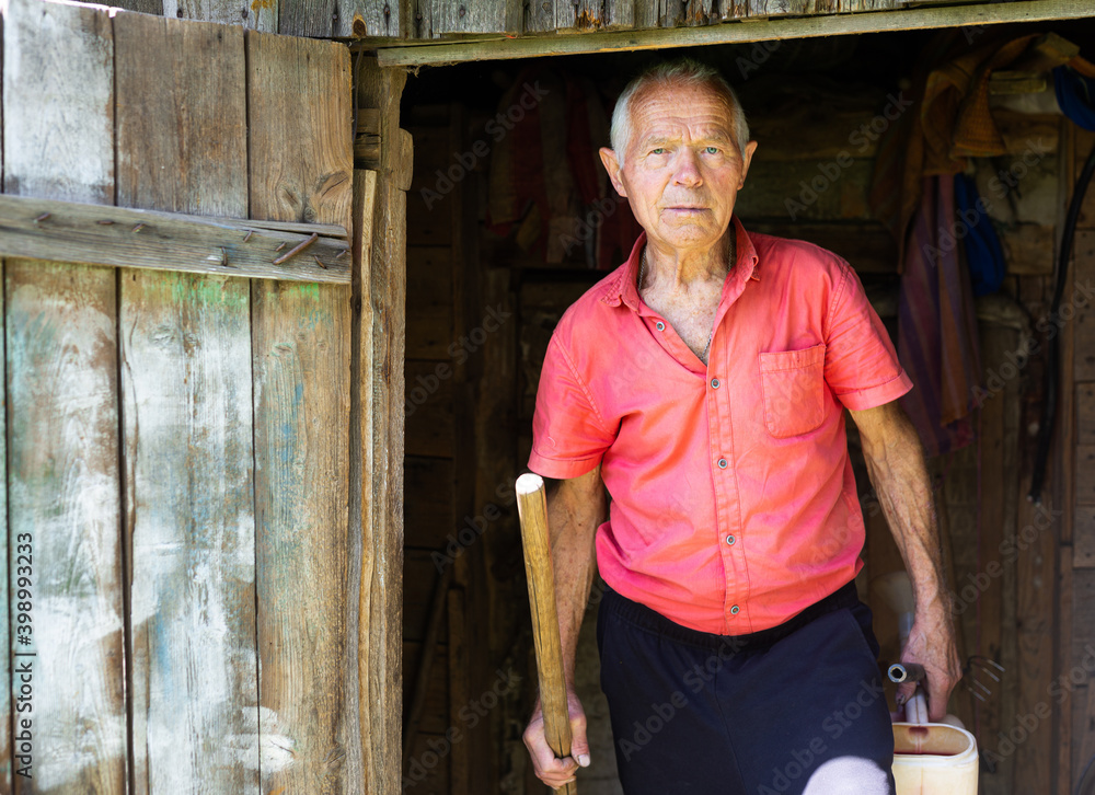 senior pensioner in red polo posing near the house in the village senior pensioner in red polo posing near the house in the village