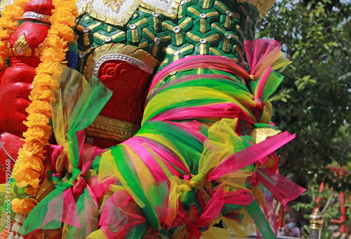 Close-up detail of colorful ribbons tied around the arm of a statue at a Buddhist temple in southeast Asia