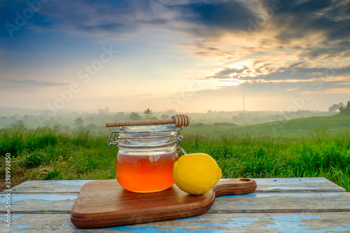 Alternative Medicine with lemon  and  honey on wooden table. Beautiful sunrise as background.