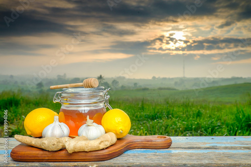 Alternative Medicine with Garlic, Ginger, Honey and Cinnamon on wooden table. Beautiful sunrise as background. photo