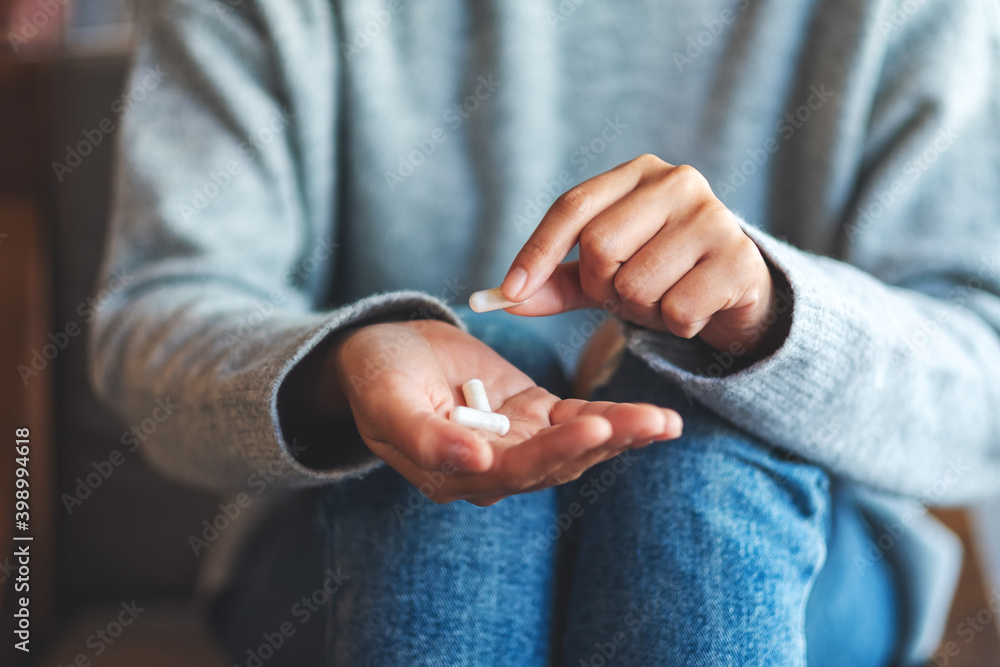 Closeup image of a woman holding and picking white medicine capsules in hand Closeup image of a woman holding and picking white medicine capsules in hand