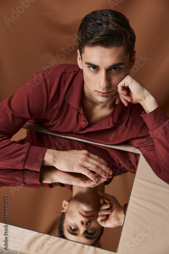a man in a shirt sits at a table reflection in a mirror fabric background
