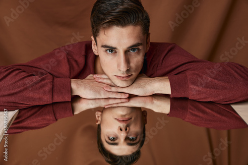 Fotografie A man in a shirt is leaning against the glass with a reflection in the mirror on