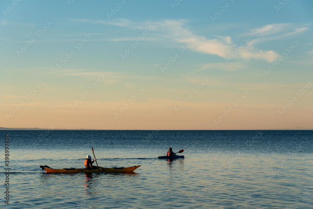 Kayakers paddling in Birch Bay in the late afternoon light, peaceful scenic landscape
