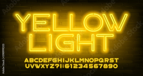 Yellow Light alphabet font. Neon light letters and numbers. Brick wall background. Stock vector typescript for your design.