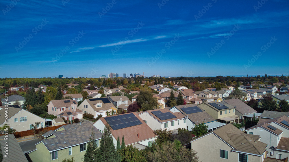 Suburban homes with solar panels with downtown high rise buildings in the distance 