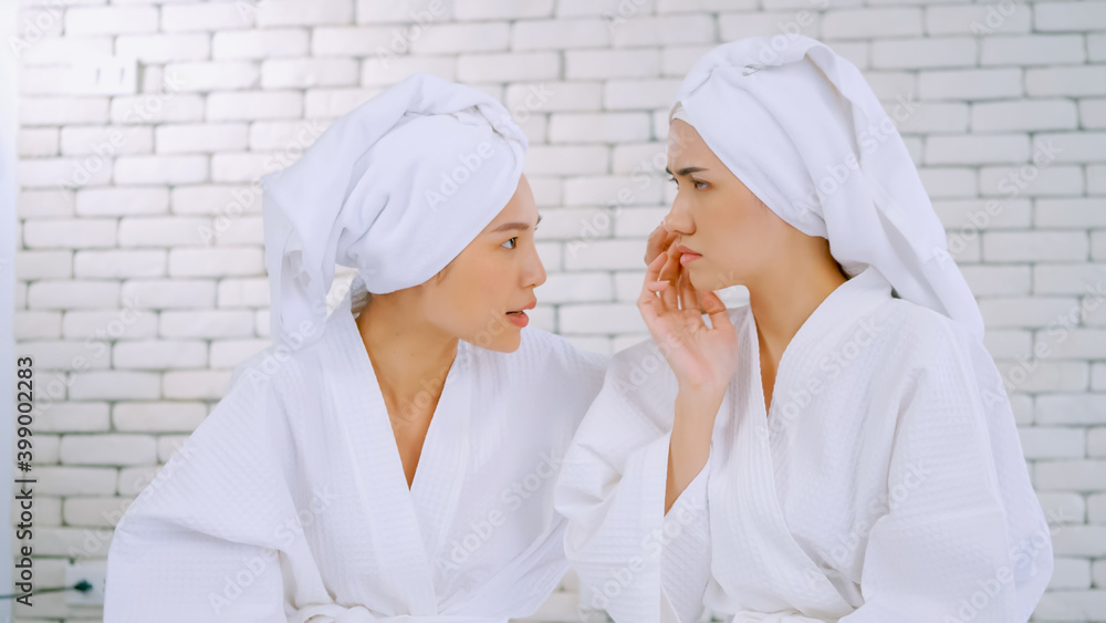 Two Asian girls in white bathrobes with towels on heads talking in living room. Two Asian girls in white bathrobes with towels on heads talking in living room.