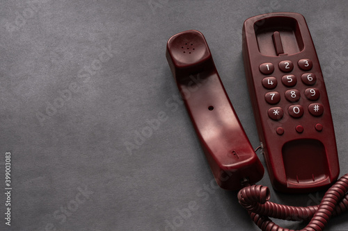 Red Old fashion landline home phone with handset off hook, on wire on grey grunge background with blank space for text.  Answer call. Pick up phone. Hang up phone. Dramatic. Copy space