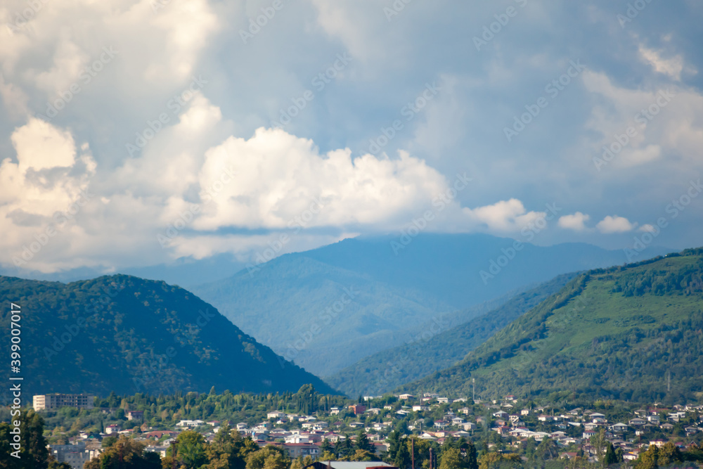 City in a mountainous hollow against the cloud sky with blurry background, used as a background or texture, soft focus