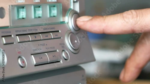 Man finger pressing play button on vintage tape player.