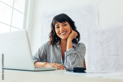 Smiling female architect sitting at her office desk