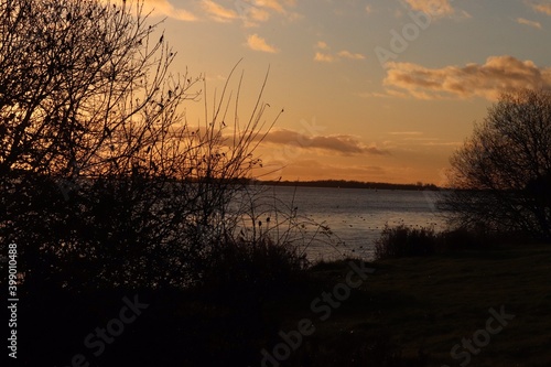 Deep glowing sun set over a nature park lake winter season 