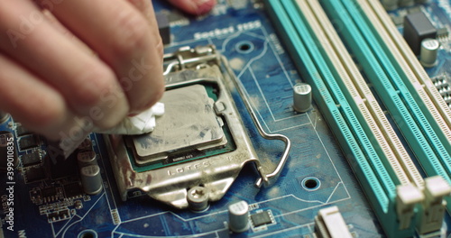 The repairman cleans the CPU of the laptop from the old thermal grease. Electronics and computer concepts service. Repair of computer boards