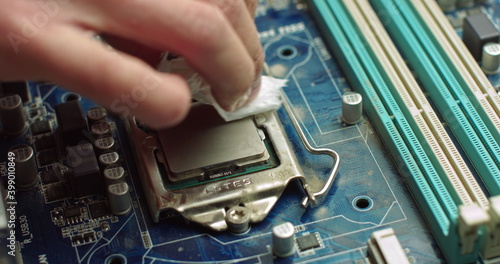 The repairman cleans the CPU of the laptop from the old thermal grease. Electronics and computer concepts service. Repair of computer boards