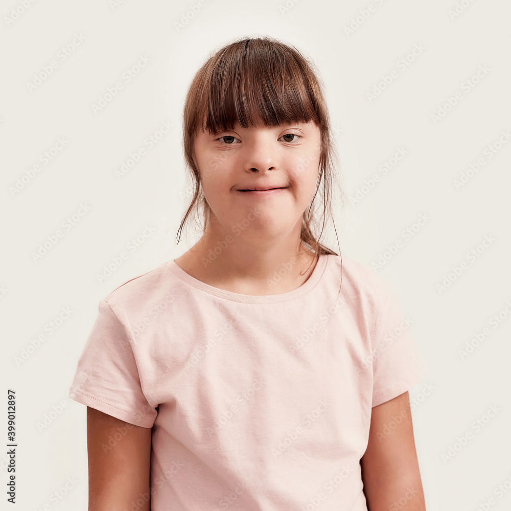 Close up portrait of disabled girl with Down syndrome smiling at camera while posing isolated over white background Close up portrait of disabled girl with Down syndrome smiling at camera while posing isolated over white background