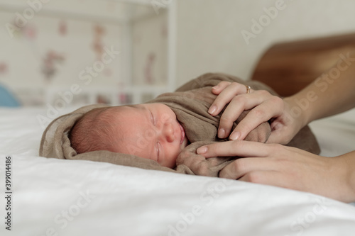 Bild auf Leinwand Young mother of a family brunette holds a newborn toddler in her arms - her tiny