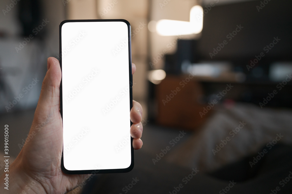 POV photo of man holding smartphone with white screen while sitting on a couch