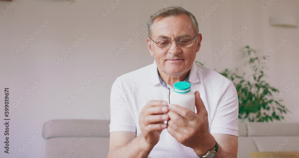 An older man reads the instructions on the pill bottle. An older man reads the instructions on the pill bottle.