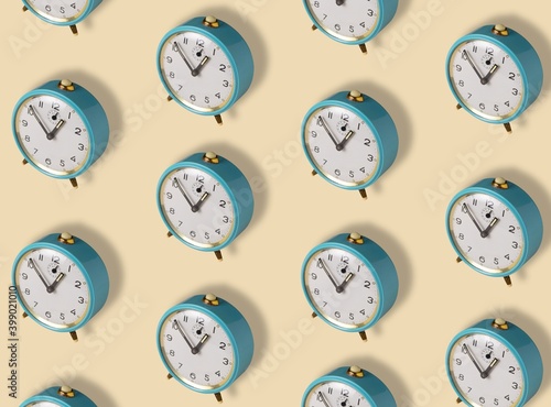 Pattern made with blue old alarm clock on yellow background