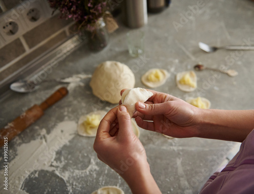 A young woman sculpts delicious dumplings in the kitchen.