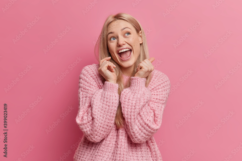 Overjoyed blonde young woman has happy face expression looks above keeps mouth opened dressed in casual clothes isolated over pink background. Attractive European girl imagines something funny Overjoyed blonde young woman has happy face expression looks above keeps mouth opened dressed in casual clothes isolated over pink background. Attractive European girl imagines something funny