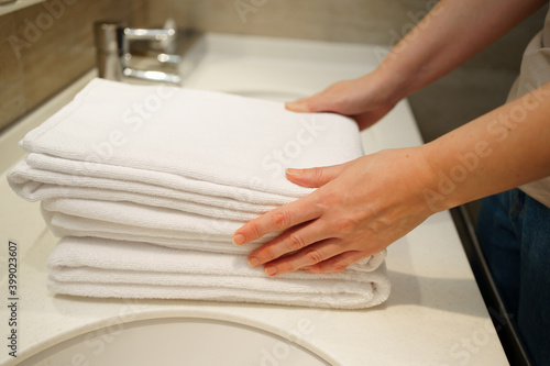 women's hands with clean white towels in hand. Replacing bath accessories.