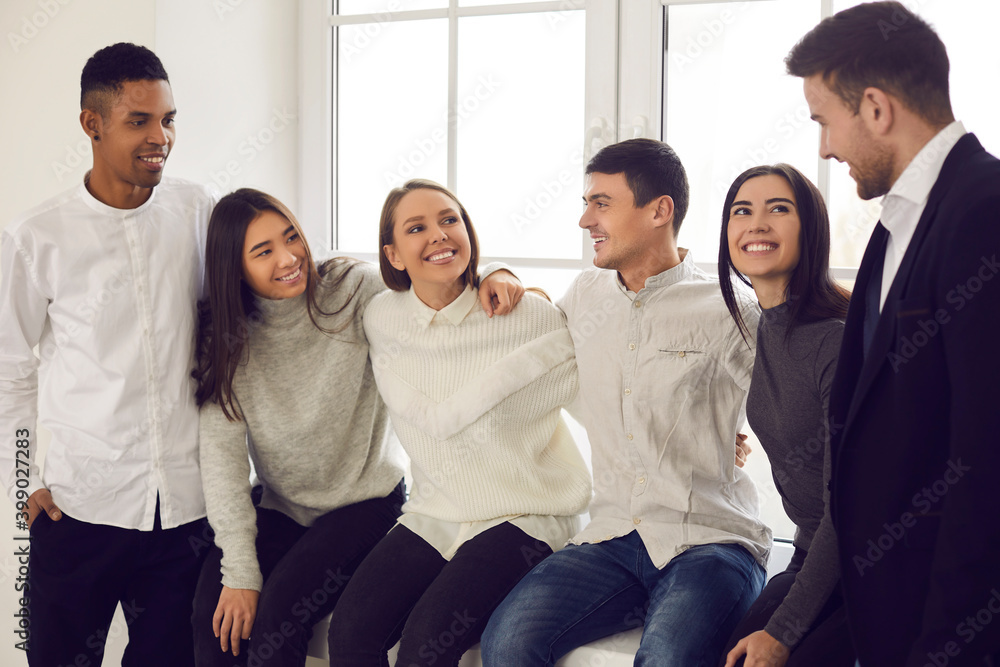 Group of cheerful multiracial students are sitting on the windowsill and talking to each other. Group of cheerful multiracial students are sitting on the windowsill and talking to each other.