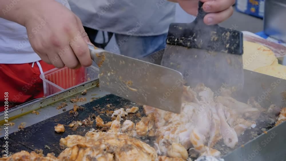 Chef holding hatchet, cutting roasted chicken meat on grill at summer local food market - slow motion, close up view. Outdoor cooking, gastronomy, cookery, street food concept Chef holding hatchet, cutting roasted chicken meat on grill at summer local food market - slow motion, close up view. Outdoor cooking, gastronomy, cookery, street food concept