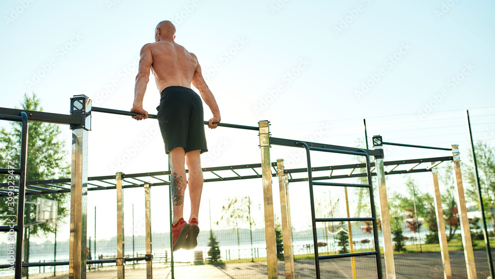 Fototapeta premium Caucasian male athlete performing exercise on horizontal bar