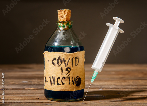Dirty artisanal bottle with a fake coronavirus vaccine made in unsanitary conditions and a syringe photo