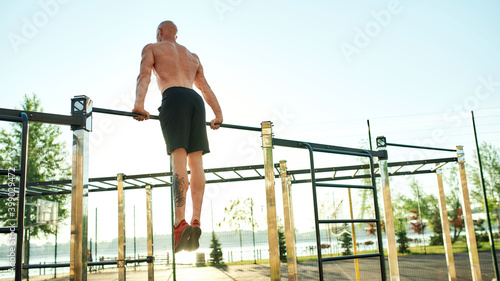 Caucasian male athlete performing exercise on horizontal bar