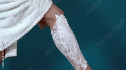 Close-up of legs of a young woman. Shave legs with shaving foam and a manual razor