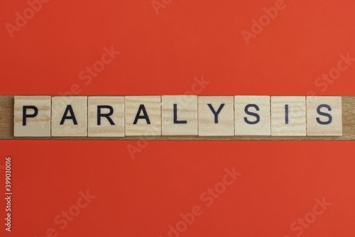 text the word paralysis from gray wooden small letters with black font on an red table