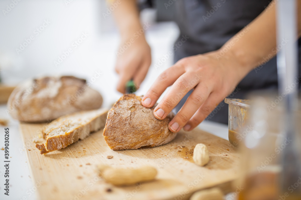Female hands slicing bread on a cutting board Female hands slicing bread on a cutting board