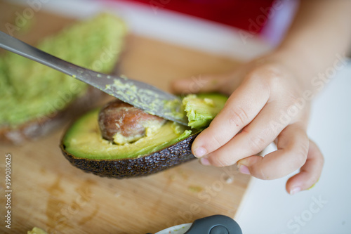 Young female hands slicing an avocado on cutting board photo