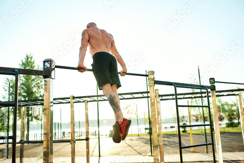 Caucasian male athlete pulling up on horizontal bar
